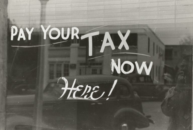 1930's tax office sign with era car in the background