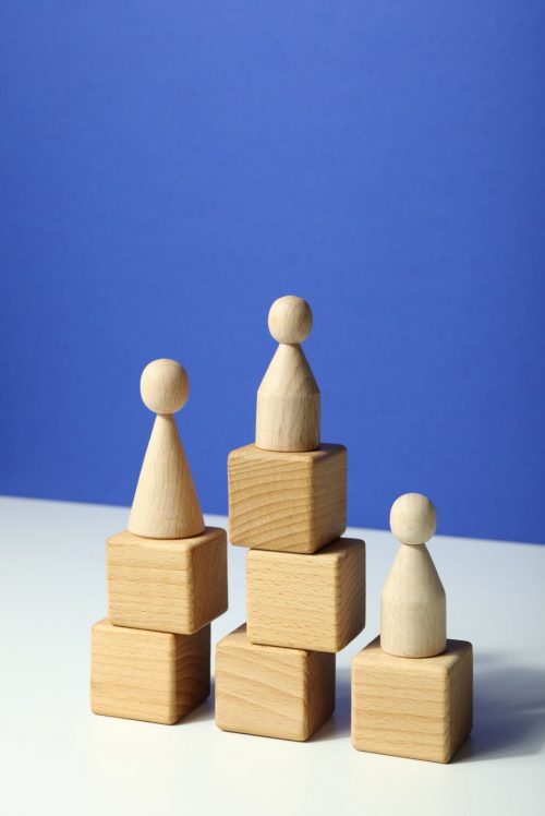 three wooden pawns signifying the necessary roles how to scale your business